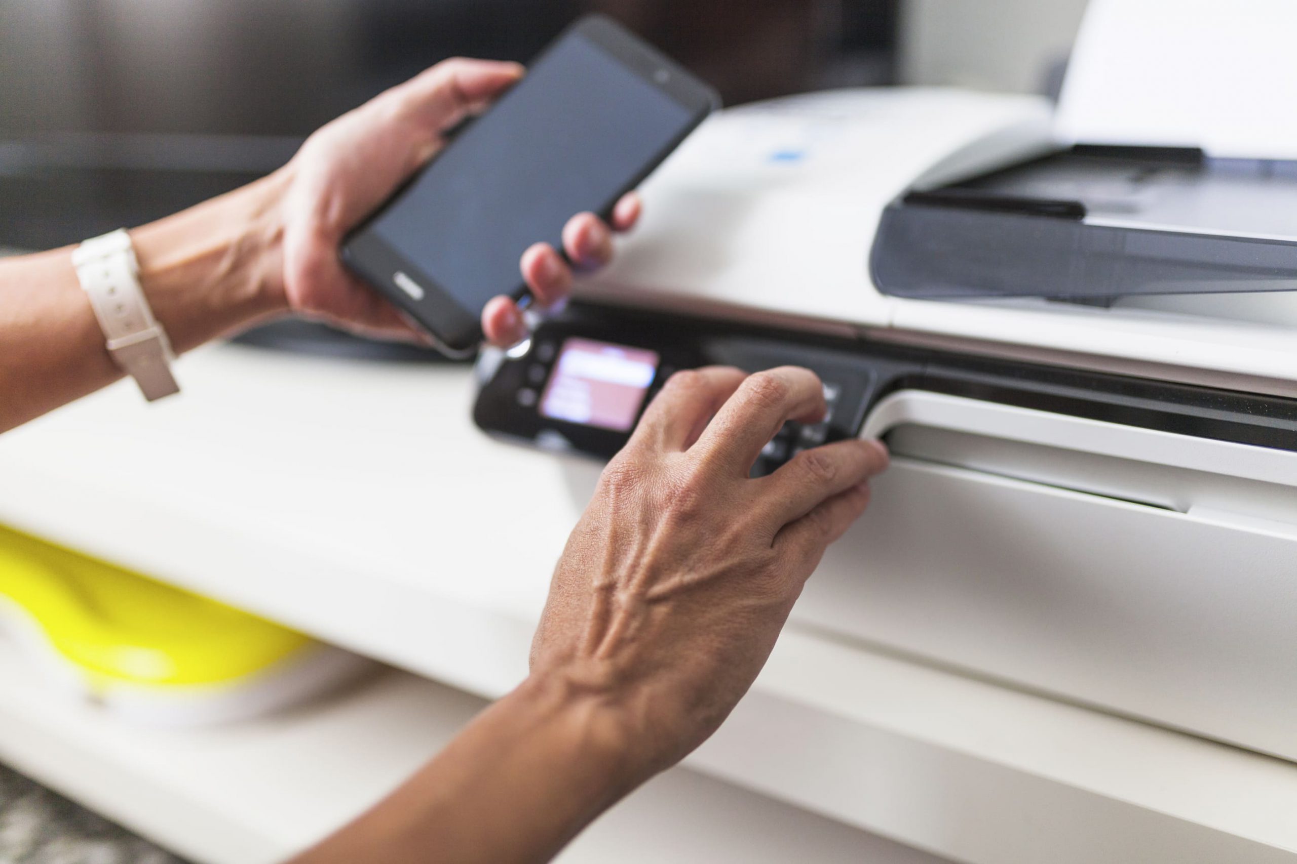 person with cell phone using a printer