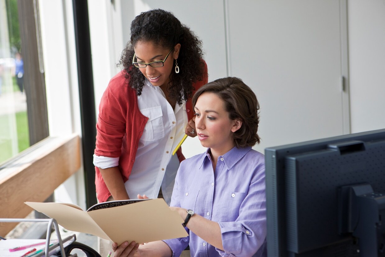 two women reading a paper