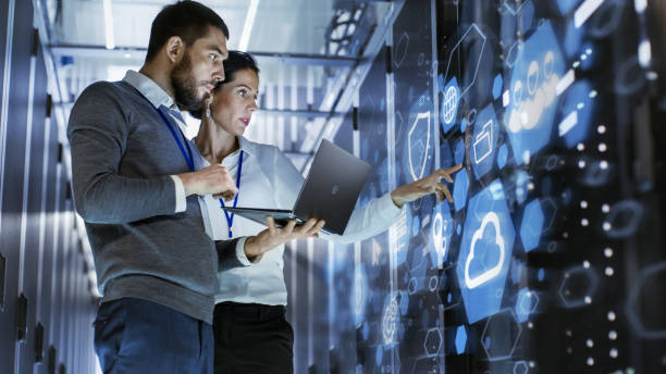 Two people are looking at a wall with data on it.