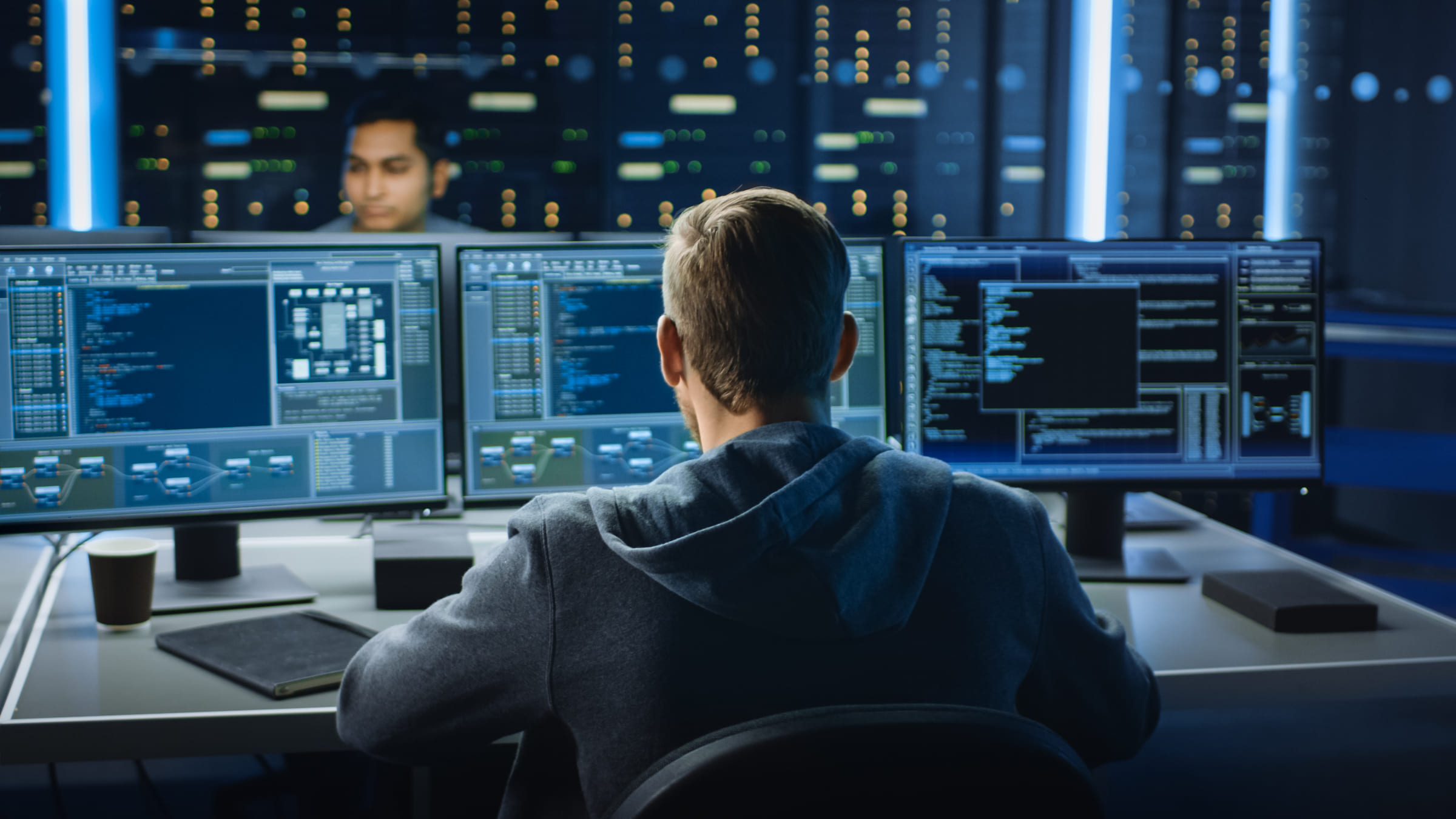 man sitting at two desktops